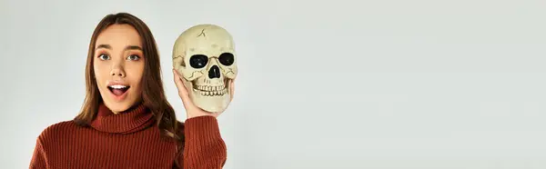 Une jeune belle femme pose joyeusement avec un crâne, se préparant pour les célébrations d'Halloween. — Photo de stock
