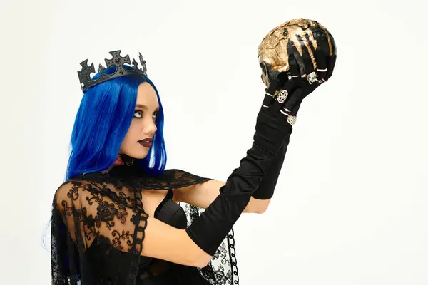 This captivating young woman wears a gothic Halloween costume, holding a skull in dramatic fashion. — Stock Photo