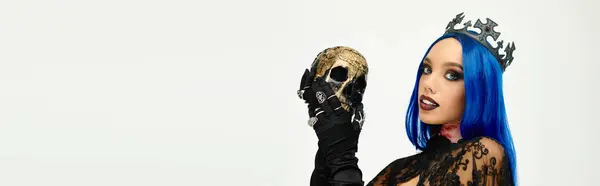 At a Halloween themed gathering, a beautiful young woman showcases her striking costume and a skull. — Stock Photo