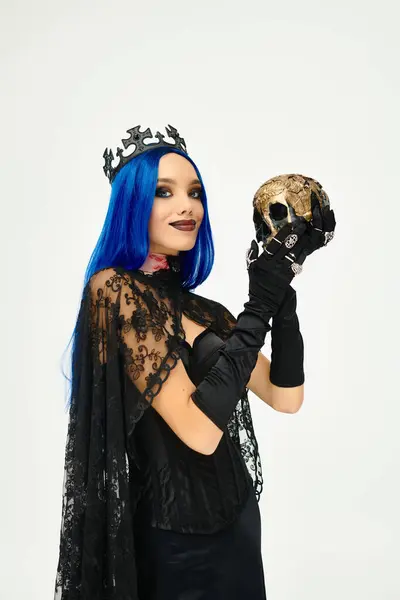 A young woman in a striking Halloween costume holds a skull, exuding dark elegance and charm. — Stock Photo