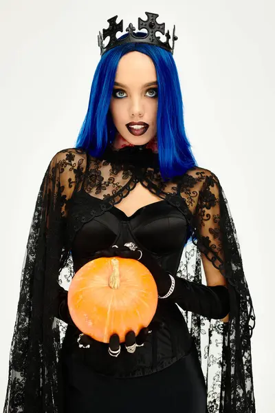 A captivating woman wears a Halloween outfit, elegantly holding a bright orange pumpkin with flair. — Stock Photo