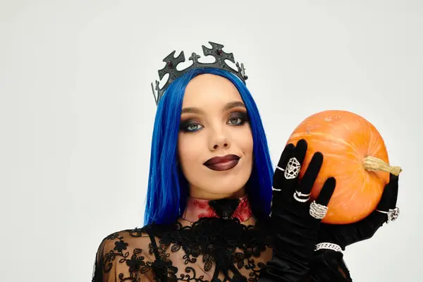 This stunning young woman showcases a creative Halloween costume while holding a bright pumpkin. — Stock Photo