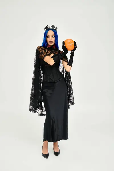 Dressed in a captivating Halloween costume, the woman showcases her style with a pumpkin. — Stock Photo