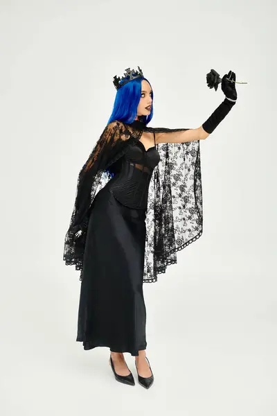 A striking young woman showcases her exquisite Halloween costume, holding a dark rose. — Stock Photo