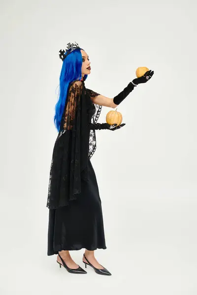 A beautiful young woman dressed in a stunning Halloween outfit holds two pumpkins, exuding charm. — Stock Photo