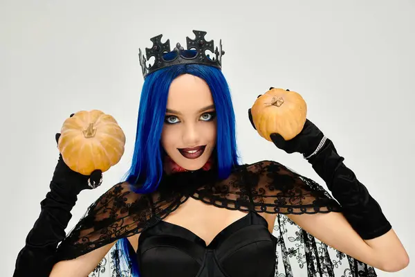 Eine schöne junge Dame im Halloween-Kostüm hält zwei Kürbisse in der Hand, die festlichen Charme versprühen. — Stockfoto