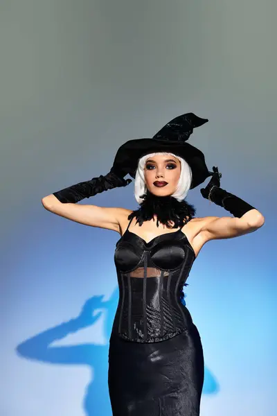 A beautiful woman showcases her Halloween spirit, wearing a striking witch costume and hat. — Stock Photo
