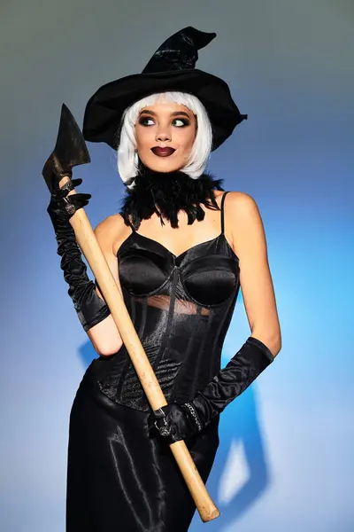 A young woman in an elegant witch costume holds an axe, embracing the Halloween spirit with style. — Stock Photo
