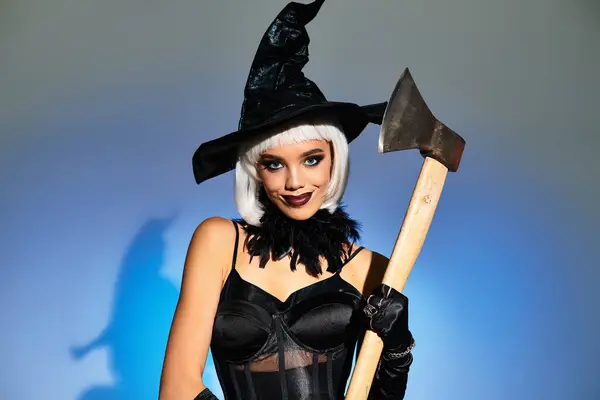 Dressed as a witch, a young woman confidently displays her axe while celebrating Halloween. — Stock Photo