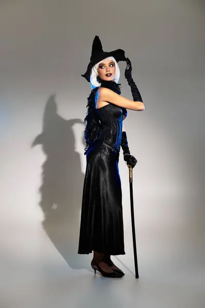 A beautiful young woman poses in an elegant witch costume, ready for Halloween festivities. — Stock Photo