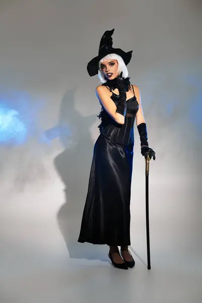 A young woman dressed as a witch showcases her enchanting Halloween costume with confidence. — Stock Photo