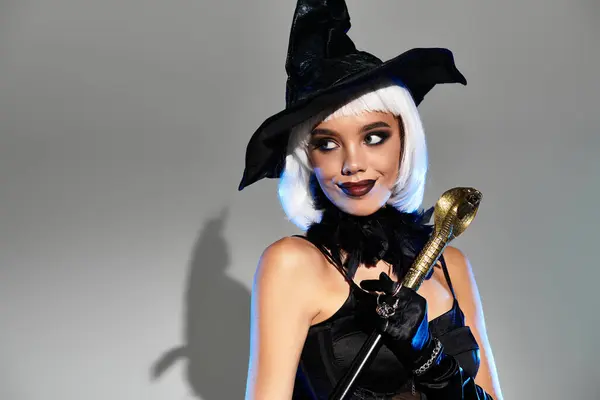 Dressed in a captivating witch costume, a young woman celebrates Halloween with charm and allure. — Stock Photo