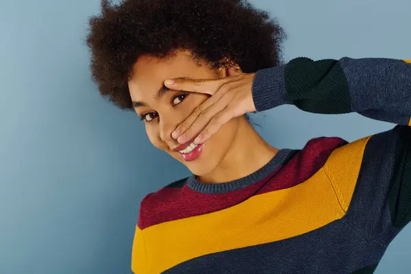 A young woman expresses her emotions playfully, covering part of her face while smiling. — Stock Photo