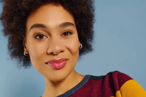 A young woman with curly hair radiates joy and confidence, dressed in colorful attire. — Stock Photo