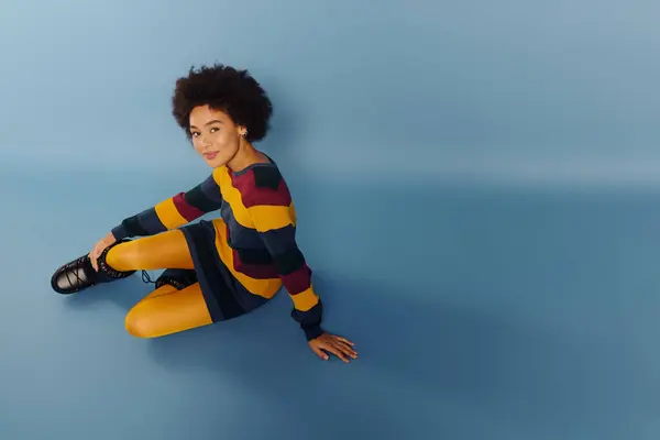 A lively young woman poses against a blue backdrop, expressing herself playfully. — Stock Photo