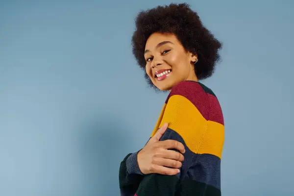 A young woman beams in a cozy sweater, surrounded by a tranquil setting. — Stock Photo