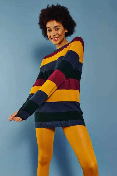 A young emotional woman in a striped sweater showcases her joy and style against a vibrant backdrop. — Stock Photo