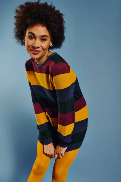 A young woman shows deep emotion in a vibrant striped sweater, creating a striking contrast. — Stock Photo