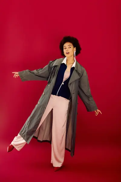 A young woman in a stylish outfit strikes a joyful pose, showcasing her vibrant emotions. — Stock Photo