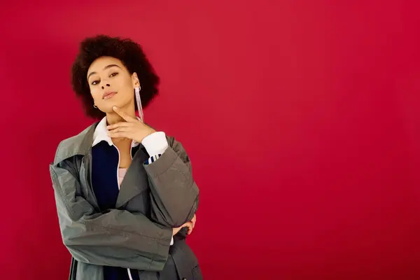 A young woman stands contemplatively amid striking red walls, exuding creativity. — Stock Photo