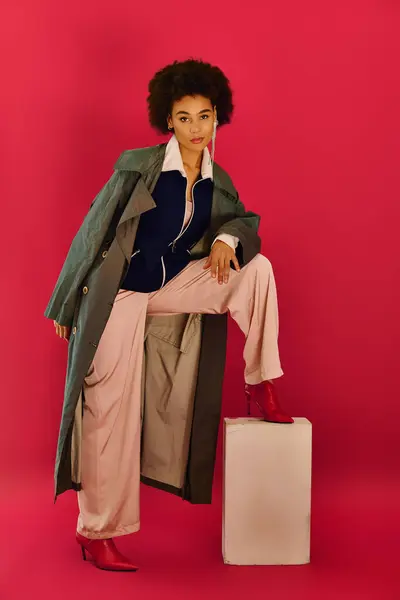 A young woman showcases her stylish outfit and strong emotions against a pink backdrop. — Stock Photo
