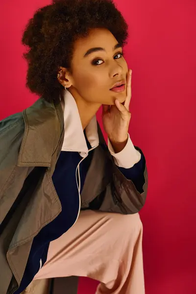 A young woman with an emotional expression leans thoughtfully against a bright pink background. — Stock Photo