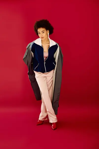 A young woman expresses deep emotion while showcasing fashionable clothing against a bold backdrop. — Stock Photo