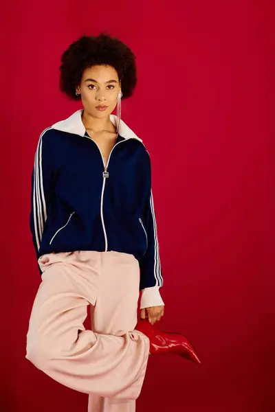 The young woman stands confidently, displaying her vibrant attire against a bold backdrop. — Stock Photo