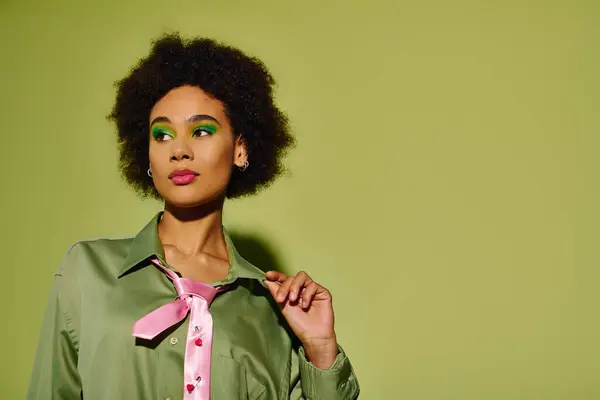 A young woman showcases her stylish outfit and deep emotions against a bold green backdrop. — Stock Photo