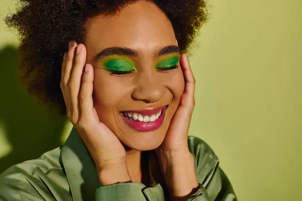 A joyful young woman with vibrant green eye makeup is smiling blissfully, embracing her emotions. — Stock Photo