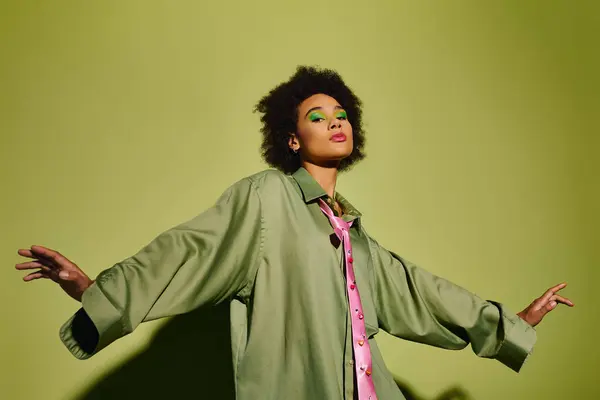 A young woman poses gracefully in unique fashion against a vibrant green backdrop. — Stock Photo