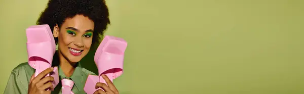 The young woman smiles brightly while holding her stylish pink footwear, exuding happiness. — Photo de stock