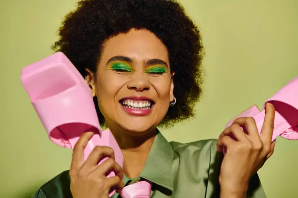 Uma jovem mulher irradia felicidade, segurando objetos coloridos rosa, mostrando sua energia vibrante. — Fotografia de Stock