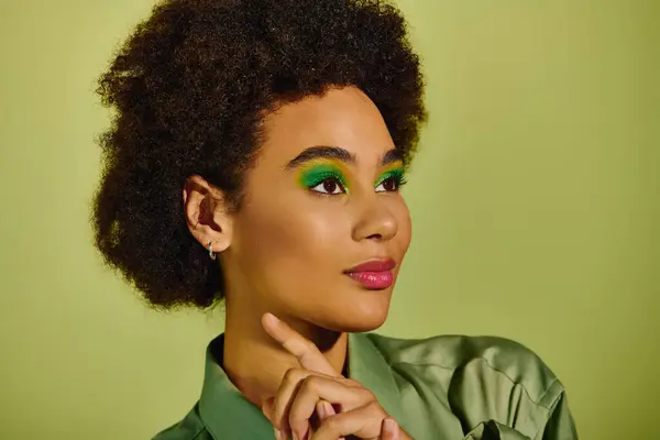 A young woman with expressive features showcases her bold green eye makeup and poses thoughtfully. — Stock Photo