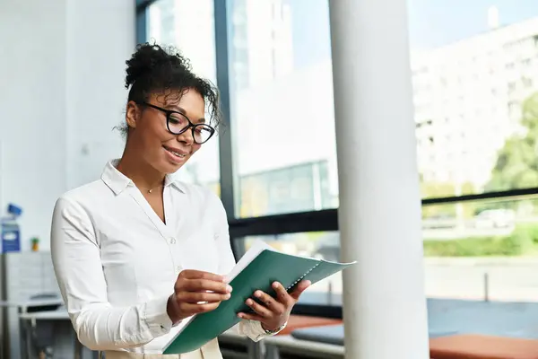 An enthusiastic teacher engages with her lesson materials in a well lit educational space. — Stock Photo