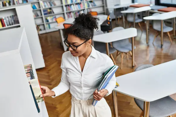 A joyful African American teacher re shelves books while guiding students in an engaging classroom. — Stock Photo