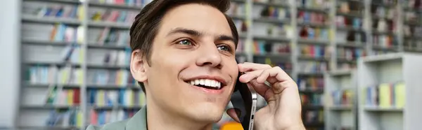 Um estudante dedicado conversa alegremente ao telefone, imerso em uma sessão de estudo em meio a estantes. — Fotografia de Stock