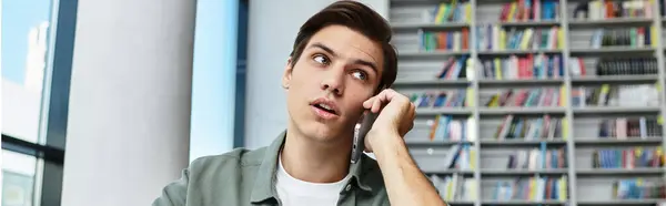 Um estudante bonito está focado em seus estudos enquanto está envolvido em um telefonema. — Fotografia de Stock