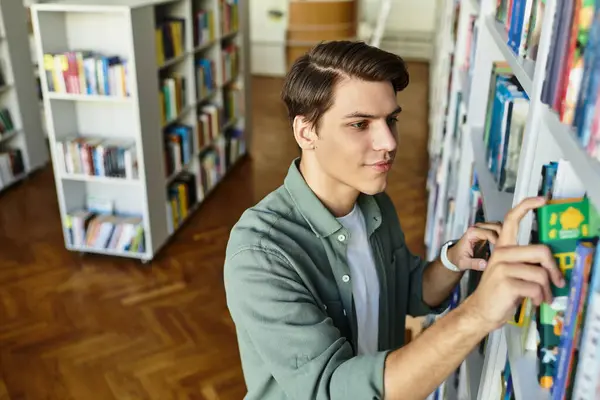 A focused student meticulously arranges books on shelves in a university library setting. — Stock Photo