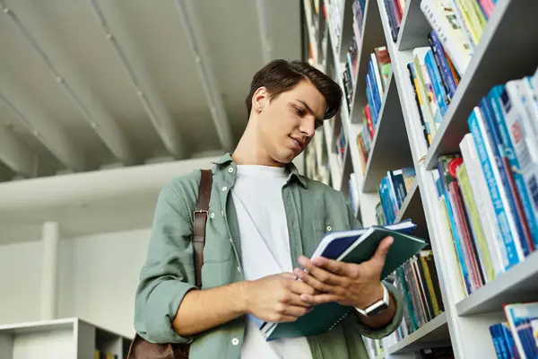 Um estudante focado navega através de livros, profundamente engajado com seus estudos em uma biblioteca moderna. — Fotografia de Stock