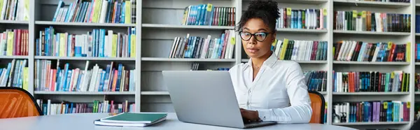 Uma professora comprometida se concentra intensamente em seu laptop, cercada por livros em uma biblioteca tranquila.. — Fotografia de Stock