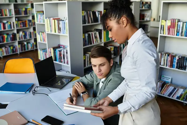 Une enseignante dévouée inspire son élève engagé dans une bibliothèque animée, nourrissant la curiosité. — Photo de stock