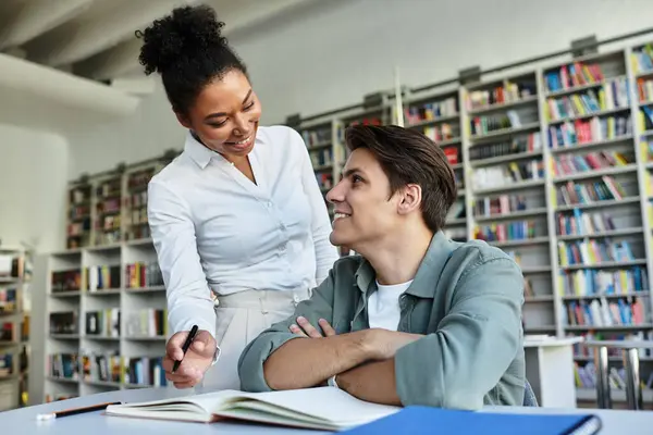 A student and mentor share an insightful conversation in a lively library, surrounded by books. — Stock Photo