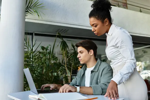 Studente e il suo insegnante lavorano fianco a fianco a un tavolo in una biblioteca, condividendo informazioni su un progetto. — Foto stock