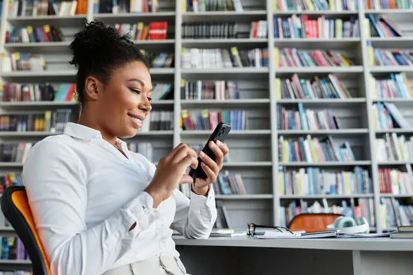 An enthusiastic teacher with phone in a vibrant library setting. — Stock Photo