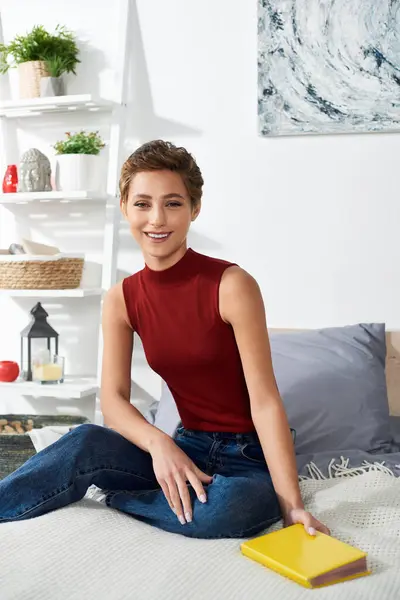 A young woman with short hair sits comfortably at home, embracing a relaxing moment while reading. — Stock Photo