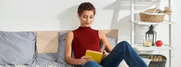 A young woman in a red tank top sits comfortably at home, writing in her journal with a serene expression. — Stock Photo