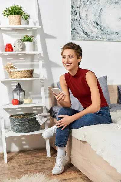 A young woman with short hair smiles while relaxing at home, enjoying her casual lifestyle and routine. — Stock Photo