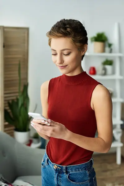 A young woman with short hair relaxes in her stylish apartment, engaged with her smartphone. — Stock Photo