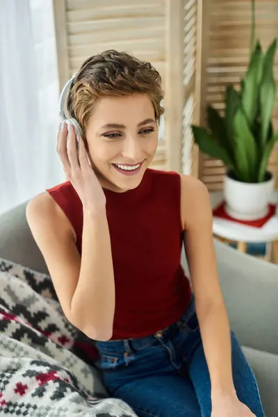 Eine fröhliche junge Frau mit kurzen Haaren entspannt sich zu Hause, ganz in einen musikalischen Moment versunken. — Stockfoto